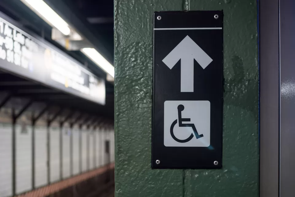 Accessible elevator sign with arrow on a New York City subway platform